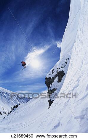 Stock Image - Skier jumping from mountain ledge. Fotosearch