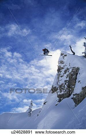 Stock Image - Skier jumping from mountain ledge. Fotosearch