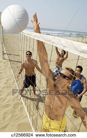 Small group of young men playing volleyball on beach outstanding the point View Large Photo Image Picture - Small group of young men playing volleyball on beach outstanding the point. Fotosearch