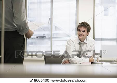 Smiling businessmen sitting in office listening to other businessman View Large Photo Image Stock Image - Smiling businessmen sitting in office listening to other businessman. Fotosearch