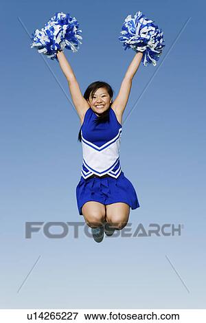 Stock Photo - Smiling Cheerleader jumping in mid-air (portrait) (low angle view). Fotosearch