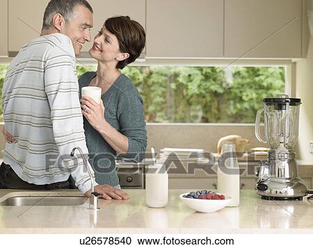 Stock Image - Smiling couple flirting in kitchen. Fotosearch
