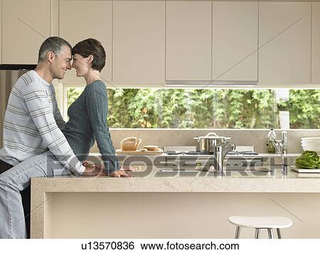 Stock Photograph - Smiling couple flirting in kitchen. Fotosearch