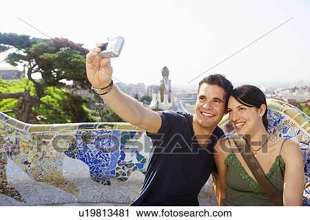 Stock Image - Smiling couple taking photo of themselves portrait. Fotosearch