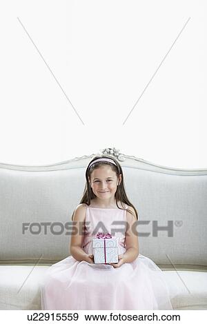 Smiling girl in tutu sitting on sofa holding gift portrait View Large Photo Image Stock Photo - Smiling girl in tutu sitting on sofa holding gift portrait. Fotosearch
