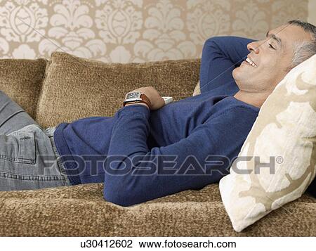 Smiling man laying on sofa View Large Photo Image Stock Image - Smiling man laying on sofa. Fotosearch
