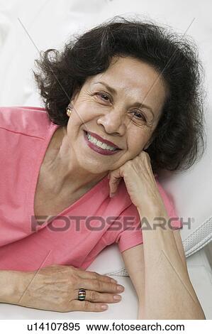 Stock Photography - Smiling middle-aged Woman on sofa portrait. Fotosearch