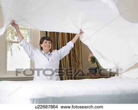 Picture - smiling woman making bed. Fotosearch