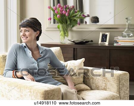 Smiling woman relaxing in living room View Large Photo Image Stock Image - Smiling woman relaxing in living room. Fotosearch