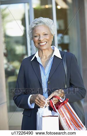 Smiling Woman standing outside holding Shopping Bags View Large Photo Image Stock Image - Smiling Woman standing outside holding Shopping Bags. Fotosearch