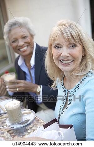 Stock Image - Smiling Women sitting Having Coffee Drinks. Fotosearch
