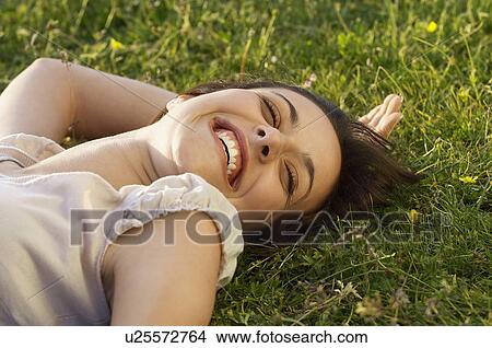 Smiling young woman lying on grass close up View Large Photo Image Picture - Smiling young woman lying on grass close up. Fotosearch