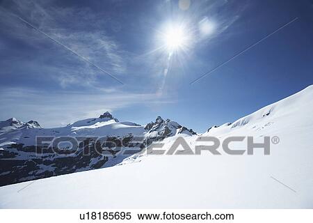 Stock Photography - Snow-topped mountain peaks under the sun. Fotosearch