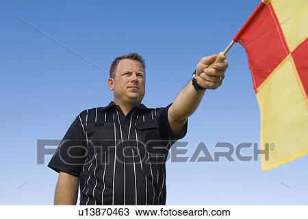 Stock Image - Soccer referee holding out penalty flag portrait. Fotosearch
