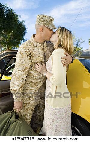 Stock Photo - Soldier kissing wife by car. Fotosearch