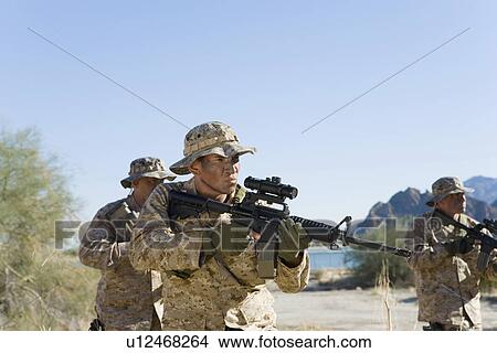 Picture - Soldiers carrying rifles in the field. Fotosearch