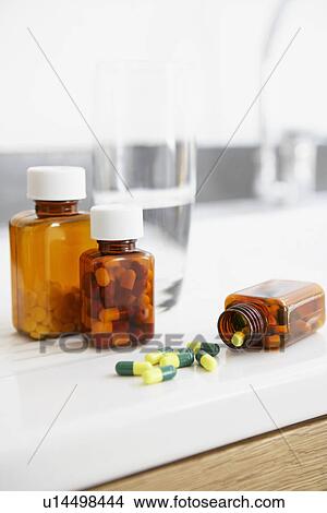 Picture - Spilt bottle of pills on counter in bathroom close up. Fotosearch