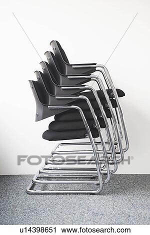 Stock Image - Stack of office chairs against wall. Fotosearch