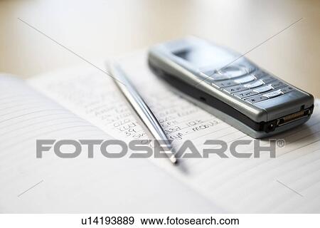 Still life of mobile phone and silver pen resting on notebook View Large Photo Image Stock Photo - Still life of mobile phone and silver pen resting on notebook. Fotosearch