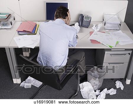 Stock Image - Stressed businessman at office desk. Fotosearch