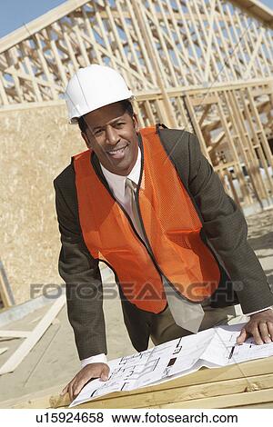 Stock Photo - Surveyor Reading Blueprints on Construction Site. Fotosearch