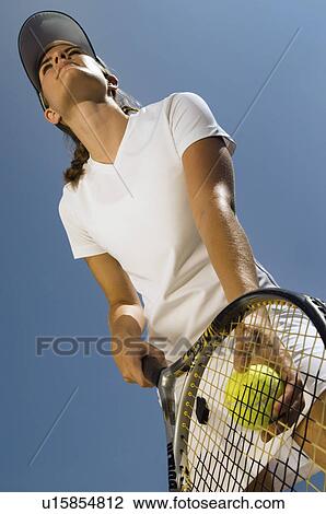 Stock Image - Tennis Player holding ball and racket Preparing to Serve low angle view. Fotosearch