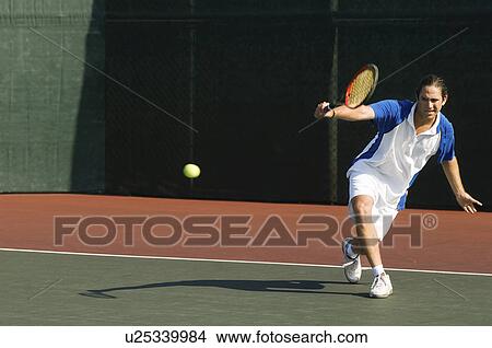 Tennis Player squatting on tennis court Hitting Backhand View Large Photo Image Picture - Tennis Player squatting on tennis court Hitting Backhand. Fotosearch