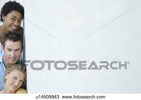 Stock Image - Three mid-adult friends leaning against the wall and looking at camera. Fotosearch