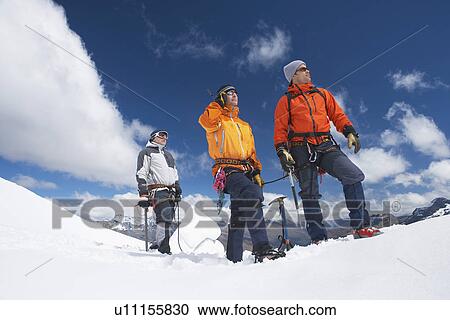 Stock Image - Three mountain climbers on snowy peak. Fotosearch