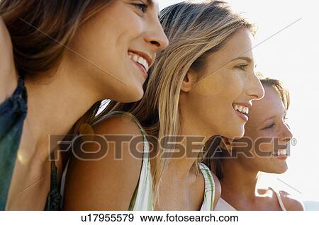 Three young women sitting side by side looking at view close up head and shoulders View Large Photo Image Stock Photo - Three young women sitting side by side looking at view close up head and shoulders. Fotosearch