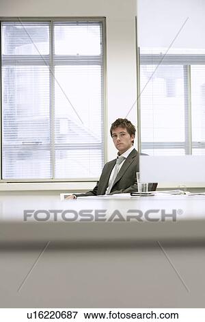 Tired Businessman sitting at desk in office View Large Photo Image Stock Photo - Tired Businessman sitting at desk in office. Fotosearch