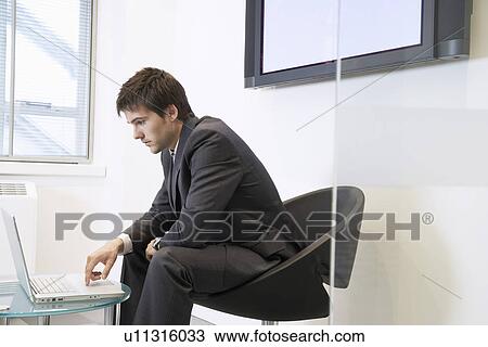 Tired Businessman Using Laptop in waiting room View Large Photo Image Stock Image - Tired Businessman Using Laptop in waiting room. Fotosearch