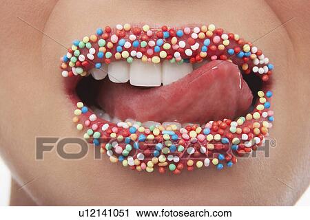 Stock Image - Tongue licking lips covered in sprinkles. Fotosearch