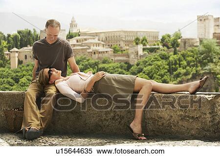 Stock Photography - Tourist Couple Relaxing on Wall in Granada Spain. Fotosearch