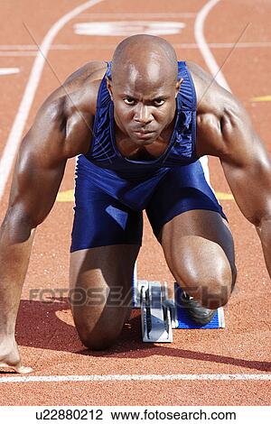 Stock Image - Track Athlete on starting block. Fotosearch