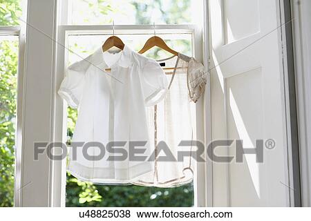 Two blouses on Hangers in domestic window View Large Photo Image Stock Photo - Two blouses on Hangers in domestic window. Fotosearch