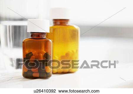 Two bottles of pills and glass of water on table close up View Large Photo Image Stock Image - Two bottles of pills and glass of water on table close up. Fotosearch