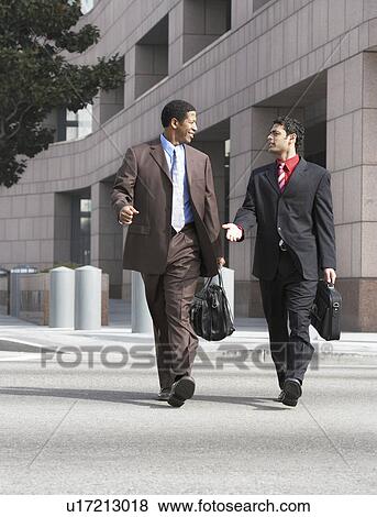 Two business men walking on city street View Large Photo Image Stock Photo - Two business men walking on city street. Fotosearch