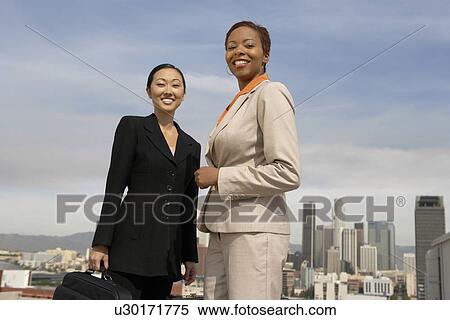 Two business women smiling in city View Large Photo Image Stock Photography - Two business women smiling in city. Fotosearch