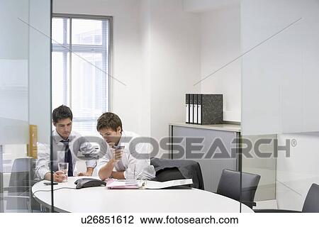 Stock Image - Two businessmen in office having conference call. Fotosearch