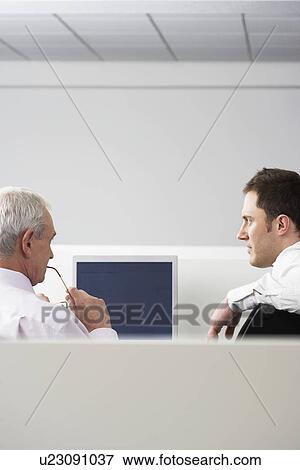 Stock Photo - Two businessmen sitting in office cubicle back view. Fotosearch