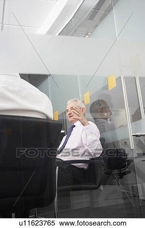 Two businessmen sitting in office behind glass wall back view View Large Photo Image Stock Photography - Two businessmen sitting in office behind glass wall back view. Fotosearch