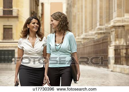 Stock Photograph - Two businesswomen walking through town together.. Fotosearch