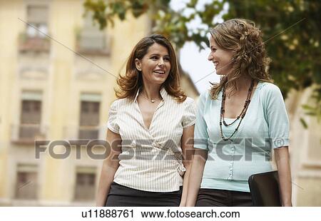 Two businesswomen walking together through old town. View Large Photo Image Stock Image - Two businesswomen walking together through old town.. Fotosearch