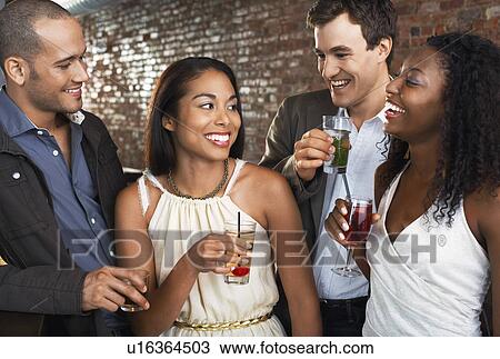 Two couples holding drinks standing in bar View Large Photo Image Stock Image - Two couples holding drinks standing in bar. Fotosearch