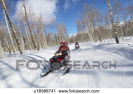 Two couples riding on two snowmobiles along snowy track View Large Photo Image Stock Image - Two couples riding on two snowmobiles along snowy track. Fotosearch