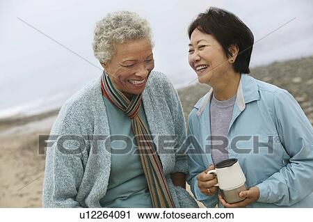 Two female friends talking on beach View Large Photo Image Stock Image - Two female friends talking on beach. Fotosearch