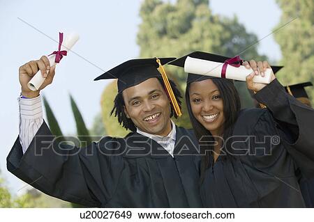Stock Photo - Two graduates hoisting diplomas outside portrait. Fotosearch