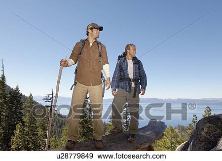 Stock Photo - Two male hikers on log near forest. Fotosearch