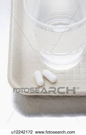 Two pills beside water in plastic cup on tray View Large Photo Image Stock Image - Two pills beside water in plastic cup on tray. Fotosearch